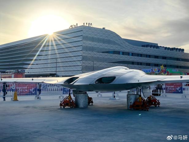 Die Stealth-Drohne KZ-2 steht vor einem modernen Gebäude bei Sonnenaufgang.