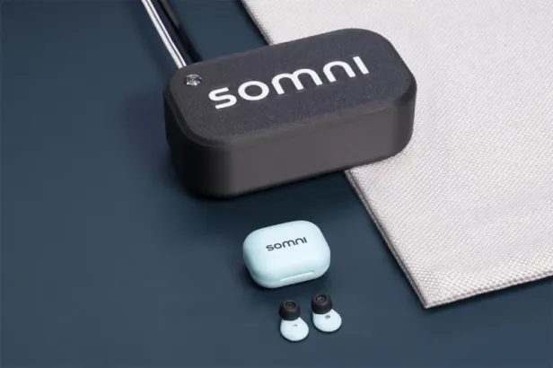 SomniBuds-Kopfhörer, Etui und Übertragungsmatte auf dunkler Oberfläche.