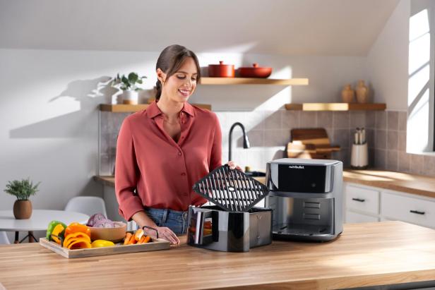 Eine Frau bereitet Gemüse für die Zubereitung in einer Nutribullet-Heißluftfritteuse vor.