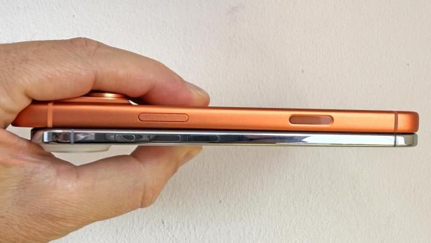 Ein orangefarbenes und ein silbernes iPhone werden nebeneinander gehalten.