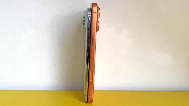 Zwei iPhones stehen nebeneinander auf einer gelben Oberfläche.