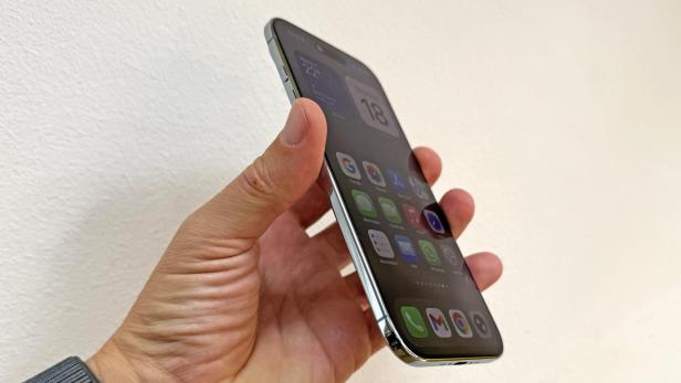 Eine Hand hält ein iPhone mit verschiedenen Apps auf dem Bildschirm.