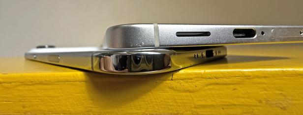 Zwei iPhones liegen übereinander auf einer gelben Oberfläche.