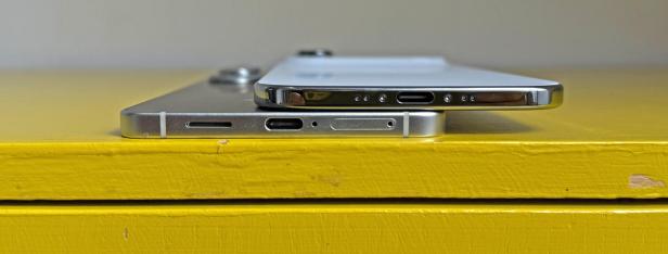 Zwei iPhones liegen auf einem gelben Tisch.