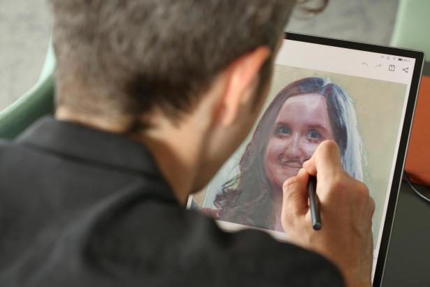 Ein Mann bearbeitet mit einem Stift ein Porträt auf einem Tablet.