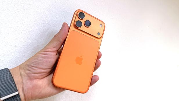 Ein orangefarbenes iPhone 17 Pro Max wird in der Hand gehalten.
