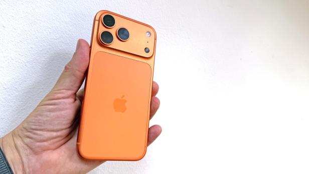 Ein orangefarbenes iPhone 17 Pro Max wird in einer Hand gehalten.