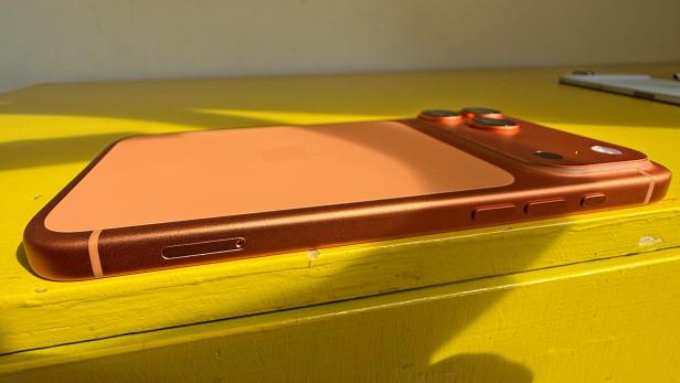 Ein orangefarbenes iPhone 17 Pro Max liegt auf einer gelben Oberfläche.
