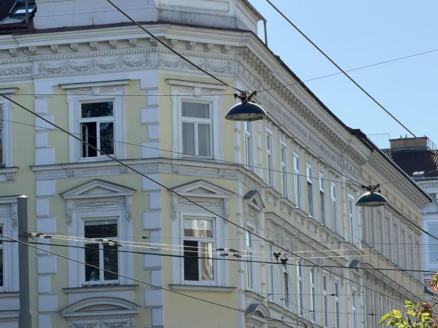 Ein gelbes Gebäude mit weißen Fensterrahmen und verzierten Fassaden unter einem blauen Himmel.