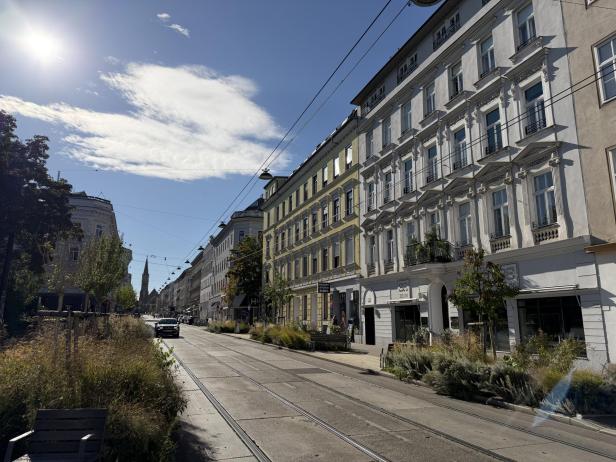 Eine Straßenbahnhaltestelle in einer Wiener Wohngegend an einem sonnigen Tag.