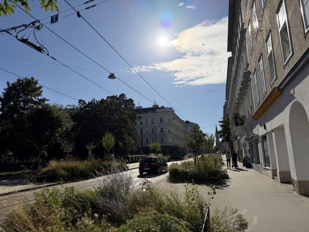 Eine Straße in einer Stadt mit einem Auto und Fußgängern auf dem Bürgersteig.