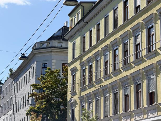 Gelbe und graue Wohnhäuser mit Stuckfassaden und Fensterläden.