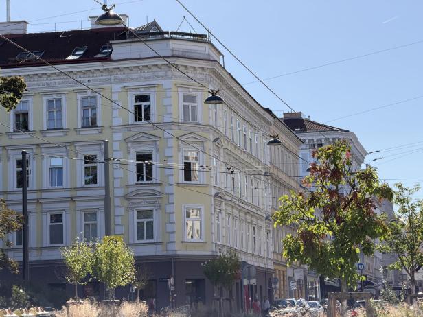 Ein gelbes Eckgebäude mit Stuckfassade in einer Wiener Straße.