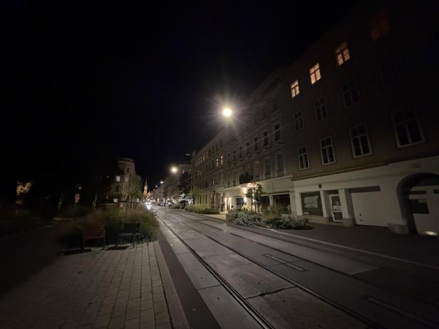Eine Straßenbahnhaltestelle in einer europäischen Stadt bei Nacht.