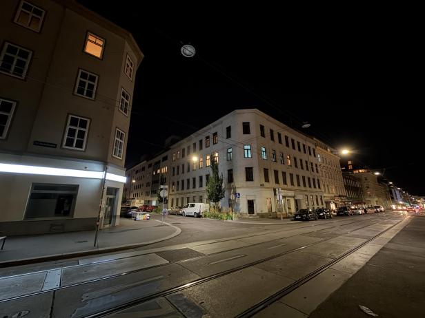Eine Straßenkreuzung in Wien bei Nacht, mit Straßenbahnschienen und beleuchteten Gebäuden.
