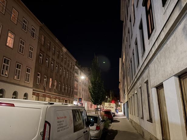 Eine nächtliche Straßenszene mit geparkten Lieferwagen und Wohnhäusern.