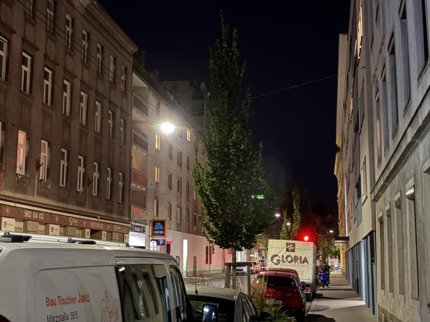 Eine nächtliche Straßenszene mit parkenden Autos und einem Lieferwagen der Firma Gloria.