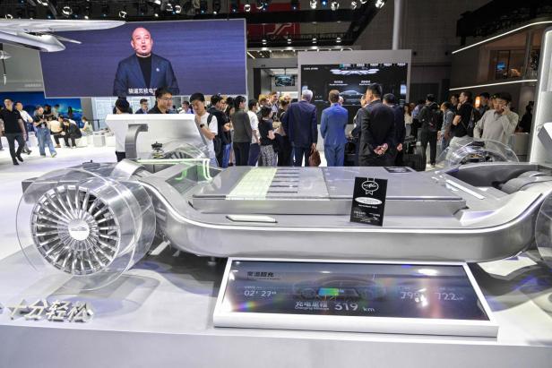 Auf einer Messe sehen Besucher ein transparentes Fahrzeugmodell und einen Bildschirm mit Ladeinformationen.