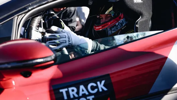 Ein Rennfahrer sitzt in einem rot-weißen „Yangwang U9 Xtreme“ Rennwagen.