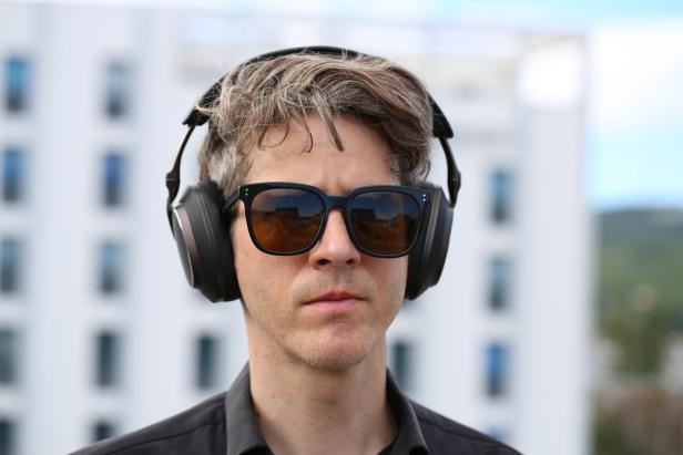 Ein Mann mit Sonnenbrille und Bowers & Wilkins PX8 S2 Kopfhörern.