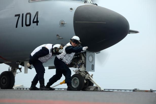 Zwei Wartungsarbeiter schieben ein Flugzeug mit der Kennung 7104 auf der „Fujian“.