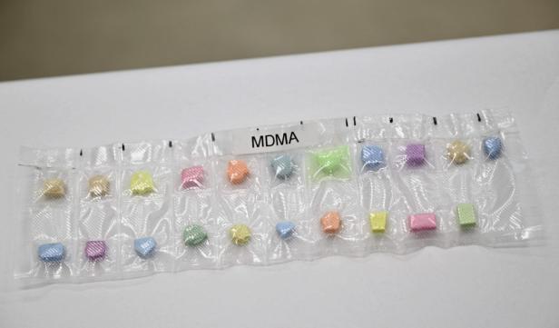 Verschiedenfarbige MDMA-Tabletten in einer durchsichtigen Blisterverpackung nebeneinander angeordnet.