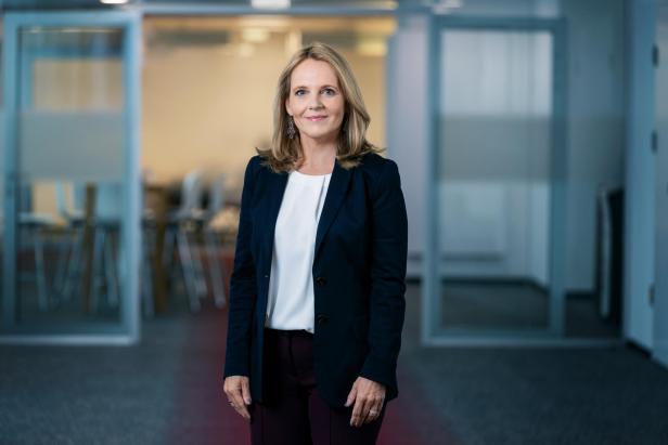 eine blonde Frau mit weißer Bluse und dunklem Anzug