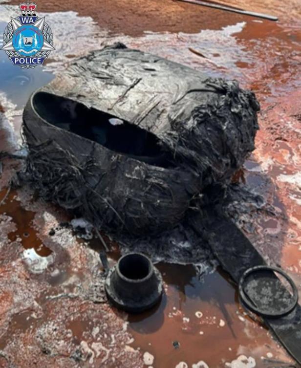 Ein verkohltes, metallisches Objekt liegt auf sandigem Boden in der Wüste von Western Australia, vermutlich ein Teil von Weltraumschrott.