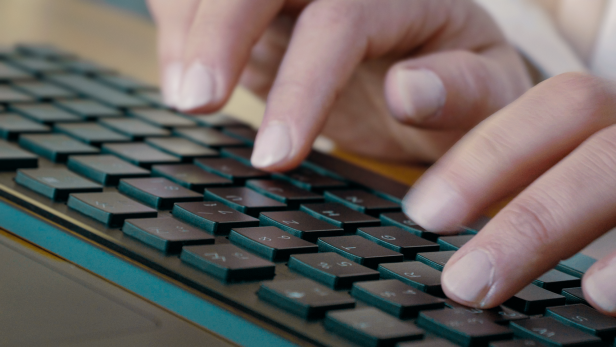 Eine Person tippt auf der ultraflachen Kompakt-Tastatur CHERRY KW X ULP 2.0 MINI mit mechanischen Tasten.