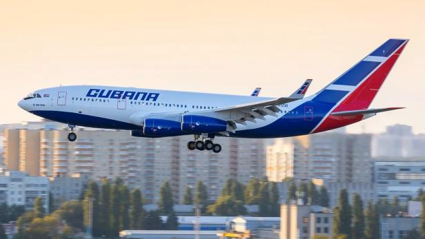 Eine Iljuschin Il-96 der Fluggesellschaft Cubana im Landeanflug vor Stadtgebäuden.