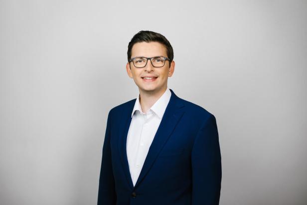 ein weißer Mann mit Brille und dunklem Anzug