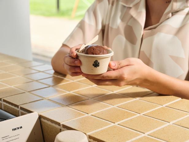 zwei Hände halten einen Becher Schokoeis