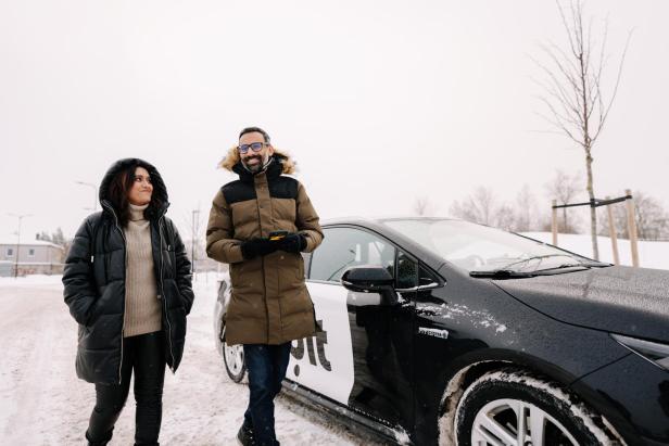 zwei Personen gehen im Winter an einem Bolt-Fahrzeug vorbei