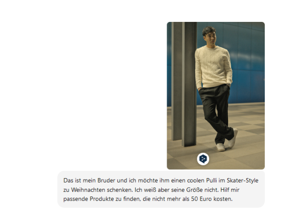 Zu sehen ist ein junger Mann mit Pullover der an einem Pfosten lehnt