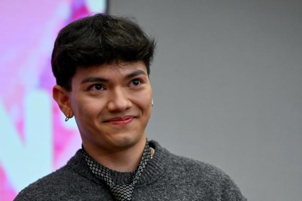 JJ  lächelt leicht vor grauem Hintergrund