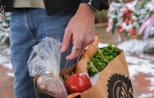 Eine Person trägt eine Einkaufstüte und trägt am Zeigefinger den smarten Edelstahlring Index 01 von Pebble.