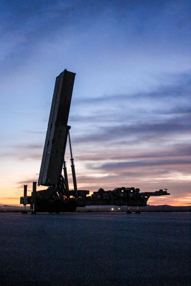 Lkw-Anhänger mit aufgerichtetem Raketenstartbehälter bei Sonnenuntergang auf freiem Gelände.