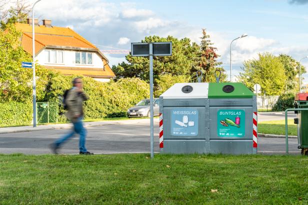 Ein Mann eilt zu einem Sammelglascontainer.