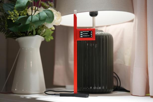 Mini-Abfahrtanzeige Straba steht auf einem Tisch vor einer Lampe
