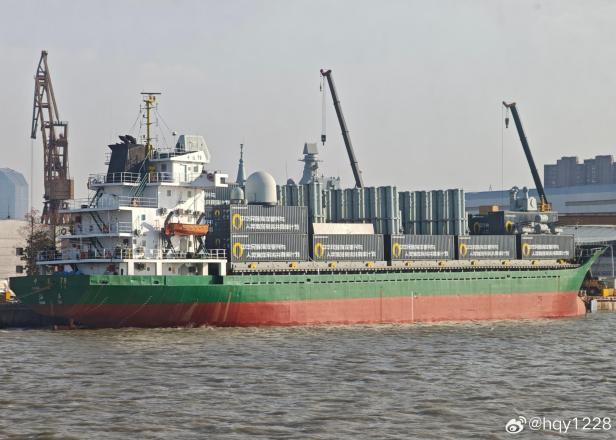 Chinesisches Frachtschiff mit zahlreichen Containern und modularen Raketenwerfern an Deck.