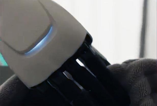 Nahaufnahme einer künstlichen Roboterhand mit schwarzen Fingern und beleuchtetem Element.