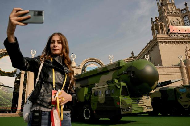 Eine Frau macht ein Selfie vor einer ausgestellten DF-41