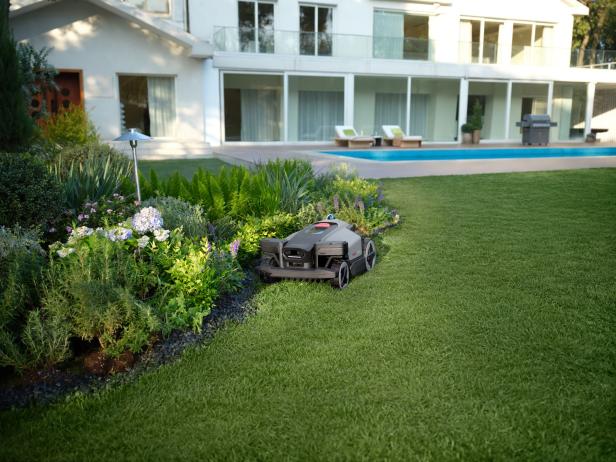 Mährroboter an der Kante zwischen Blumenbeet und Rasen.