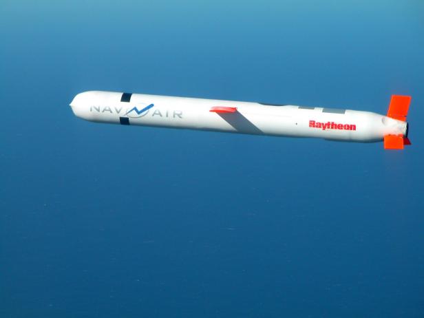 Ein US-amerikanischer Tomahawk-Marschflugkörper mit Raytheon-Logo fliegt über das Meer.