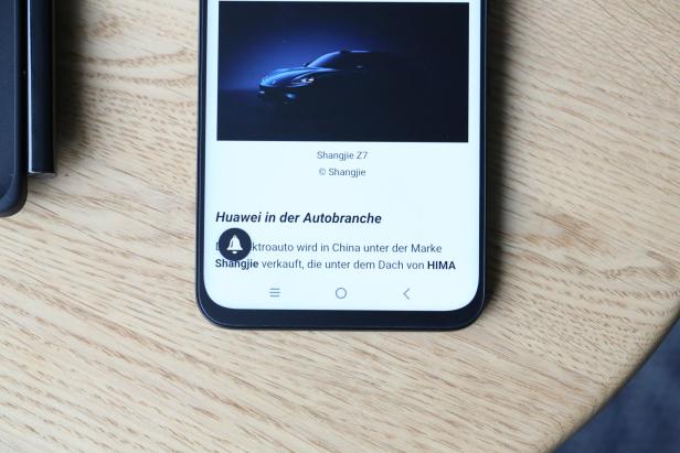 Das TCL Nxtpaper 60 Ultra liegt auf einem Holztisch und zeigt auf seinem matten Display einen Artikel über Huawei in der Autobranche.