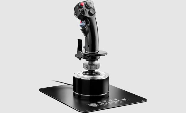 Schwarzer Joystick mit mehreren Tasten und Schaltern auf einer Metallplatte vor grauem Hintergrund.