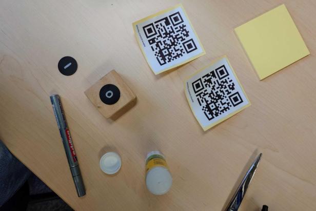 Holzklotz, NFC-Tags, Kleber, Schere, Stift und ausgedruckte QR-Codes