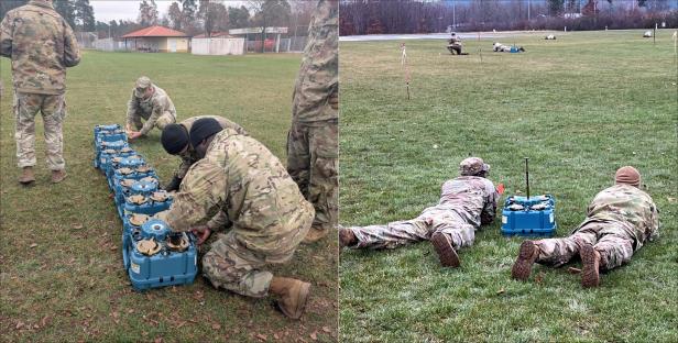 Soldaten in Tarnuniform bereiten blaue XM204-Systeme auf einer Wiese für den Einsatz vor.