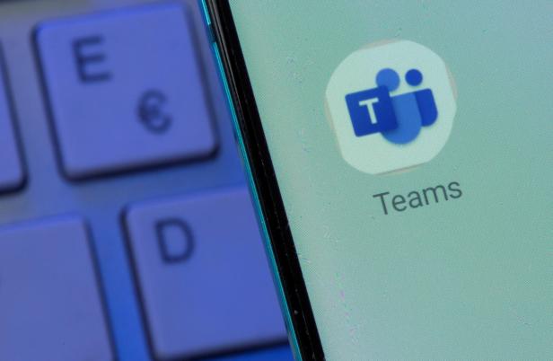 Auf einem Smartphone-Bildschirm ist das Microsoft Teams-Symbol neben einer Computertastatur zu sehen.