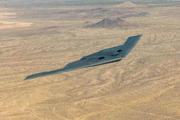 Die B-2 Spirit fliegt als Nurflügler mit großer Spannweite über eine Wüstenlandschaft.